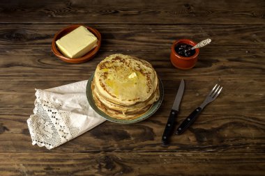 Ulusal Rus mutfağı. Bir sürü taze, sıcak, fırında krep, yeşil tabakta tereyağı ve ahşap bir masada yakın plan bir kasede reçel..