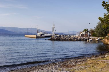 Terk edilmiş, kumlu sahil ve demirli tekneleri olan iskele sonbahar ve güneşli bir günde (Yunanistan)).