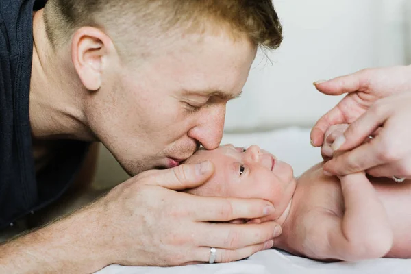 Young dad kisses a newborn on the forehead. Young dad kisses a newborn son on the forehead.