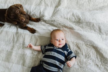 Çocuk köpeğin yanındaki yatakta yatıyor..