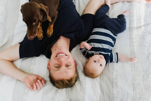 Dad Baby Smiling Looking Camera While Lying Bed Dog Nearby — Stock Photo, Image