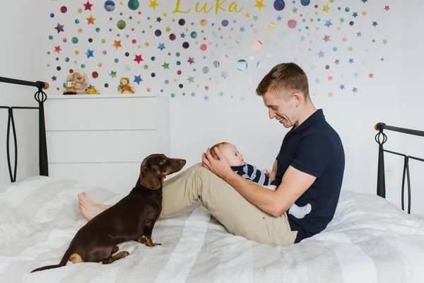 Papai Segura Bebê Sorri Enquanto Olha Para Ele Cachorro Senta — Fotografia de Stock