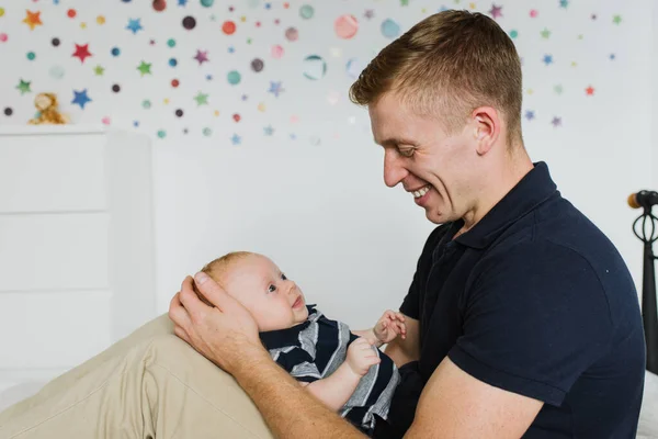 Papai Segura Bebê Sorri Enquanto Olha Para Ele — Fotografia de Stock