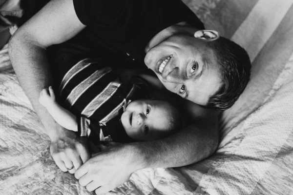 Yatakta Bebekle Kameraya Bakıp Gülümseyen Bir Babanın Siyah Beyaz Fotoğrafı — Stok fotoğraf