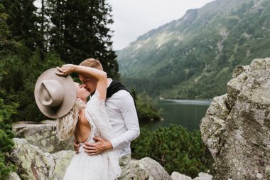 Boho tarzı elbiseli güzel gelin ve damat dağlarda sarılıyor..