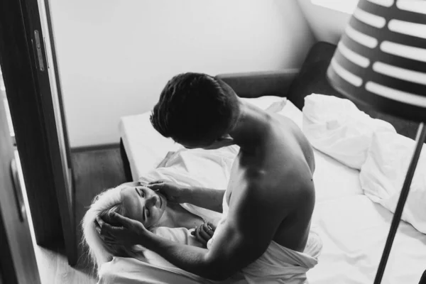 若い男と女がベッドで抱き合っている 男はベッドで女を見る — ストック写真