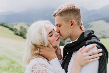 Güzel gelin boho tarzı bir elbise ve damat dağlarda sarılıp öpüşüyor..