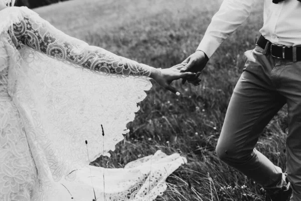 一个男人的手牵着一个女人的手穿着布荷风格的衣服 新婚夫妇的手放在自然特写上 — 图库照片