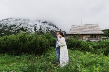 Güzel gelin ve damat dağlarda sarılıp öpüşürler..