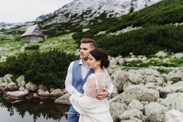 美丽的新娘和新郎在湖边的山上拥抱和亲吻 — 图库照片