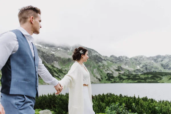 美丽的新娘和新郎在湖边的山上散步 — 图库照片