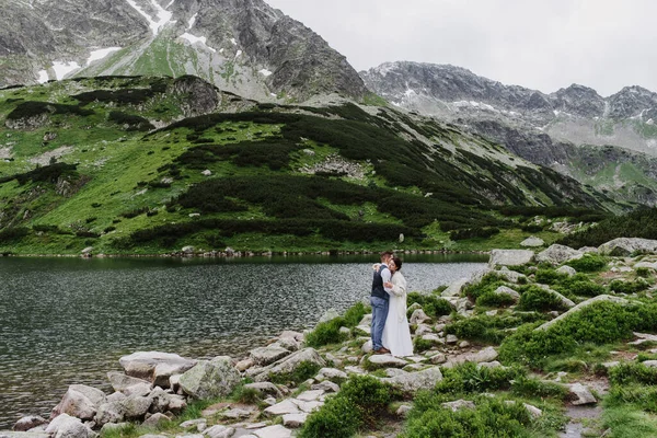 Beautiful bride and groom hug and kiss in the mountains.