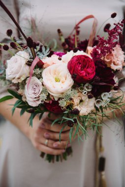 Gelinin ellerinde çok renkli bir gül buketi var. Gelinin elinde düğün buketi.