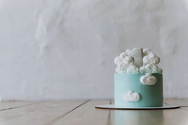 Blue cake with clouds and a unity on a white background. Little blue cake for the first year of the baby.