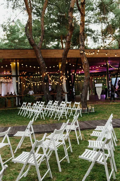 Gyönyörű Esküvői Szertartás Erdőben Fehér Székek Izzók Díszítik Esküvői Ceremóniát — Stock Fotó