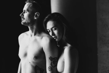 Stüdyonun penceresinin yanında yarı çıplak kadın ve erkeklerin siyah-beyaz fotoğrafı..