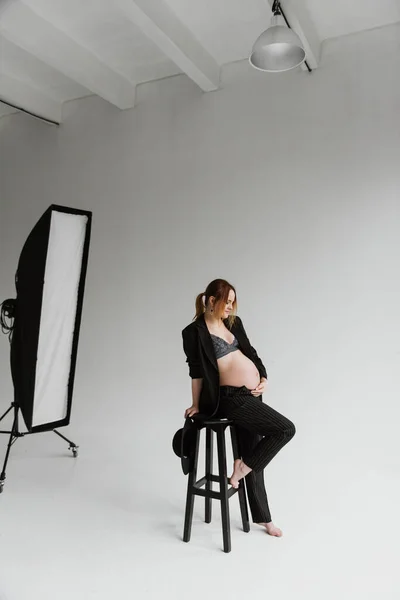 若いです妊娠中の女性でA黒スーツでザ スタジオ上の白の背景 — ストック写真
