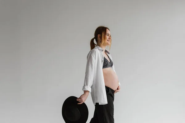 穿着内裤 白衬衫和帽子的年轻孕妇在演播室里 — 图库照片