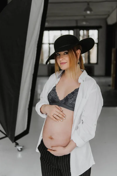 下着を着た若い妊婦 白いシャツとスタジオの帽子 — ストック写真