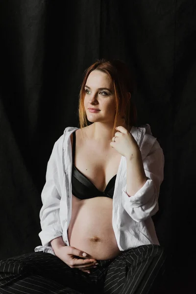 若いです妊娠中の女性で下着と白いシャツの近くの生地の背景にスタジオ — ストック写真