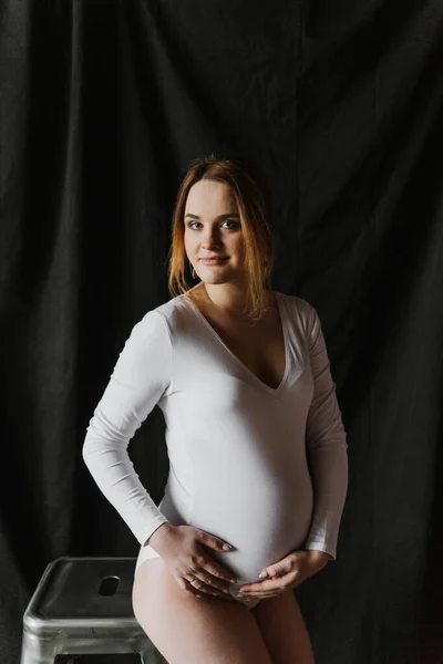 若いです妊娠中の女性で白いボディスーツ — ストック写真