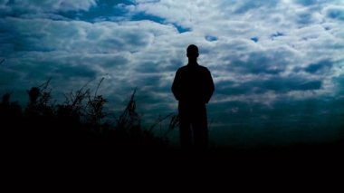 Silhouete adamın rüzgarlı gün yükseltilmiş silah ile taş taş üzerinde duruyor. Yavaş yavaş