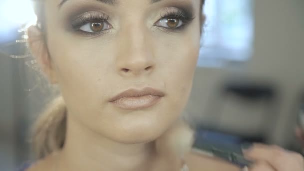 Makeup artist apply makeup to an attractive young woman — Stock Video