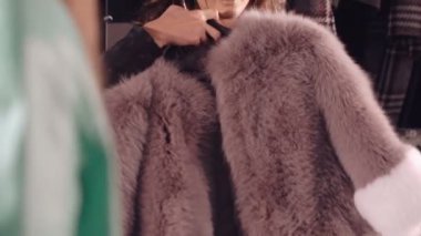 Mutlu kadın butik aynaya için zengin kürk manto üzerinde çalışıyor