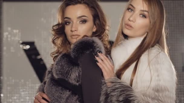Två modeller står i pose i pälsar i fashionabla rika boutique. Långsamt — Stockvideo