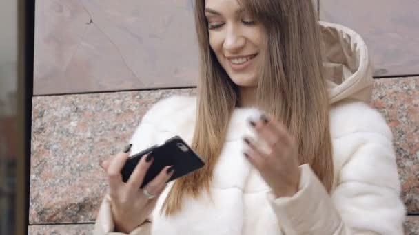 Okos lány vesz selfie, prémes dzseki az épület közelében — Stock videók