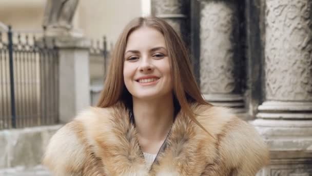 Menina bonito posando em casaco peludo na rua e sorrindo — Vídeo de Stock