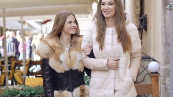 Дві гламурні дівчата ходять у пухнастих пальто в торговому центрі. Повільно — стокове відео
