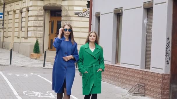 Две женщины ходят по улице в кашемировых пальто. Медленно. — стоковое видео