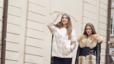 İki güvence kadın sokakta kürklü Mont pist yürür. Yavaş yavaş