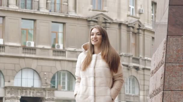 Mujer con estilo en abrigo peludo pasea por la pasarela y sonríe en la calle. Despacio. — Vídeos de Stock