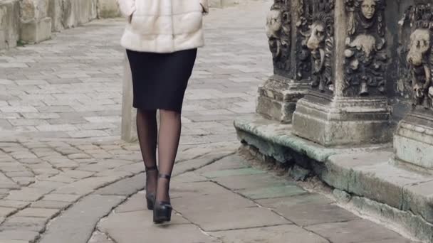 Una mujer guapa con abrigo peludo camina por la calle. Despacio. — Vídeo de stock
