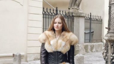 Kürklü ceket poz ve sokakta gülümseyen sevimli kız. Yavaş yavaş