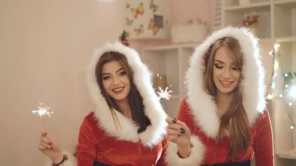 Due ragazze in abiti di Capodanno che ballano con le scintille al coperto in 4K — Video Stock