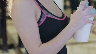 Çekici beyaz kız içme bir protein shake içki ve spor salonunda gülümseyen