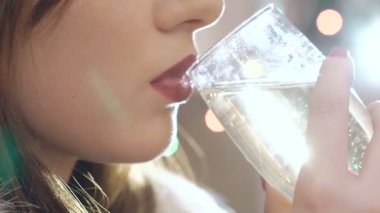 Şampanya içmek ve kameraya gülümseyen güzel kadın kapatın. Yavaş yavaş