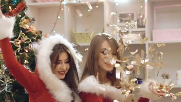 Glamour festive girls watching photos on phone in falling gold glitter. Slowly — Stockvideo