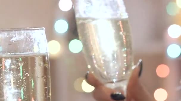 Two glasses with champagne toasting over holiday bokeh blinking background — Stock video