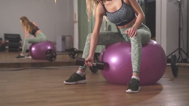 Primer plano de la deportista levantando pesas delante de la cámara en el gimnasio — Vídeos de Stock