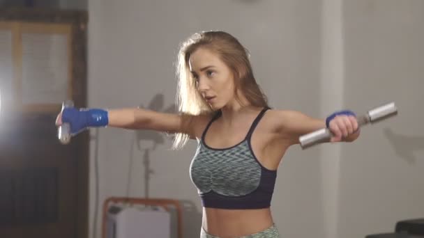 Умная девушка поднимает гантели в спортзале — стоковое видео