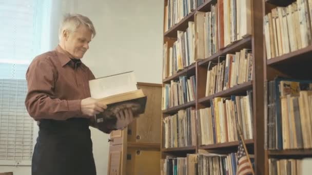 El viejo hojeando el libro en la habitación 4k — Vídeo de stock
