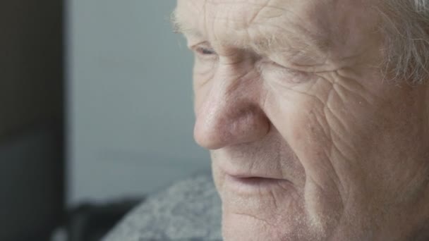 Старый дед смотрит в окно — стоковое видео