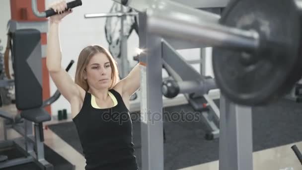 Chica haciendo ejercicio con simulador para músculos en brazos y espalda en el gimnasio en 4K — Vídeos de Stock