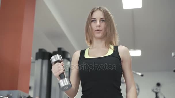 Mladá dívka s němý zvony pro biceps v tělocvičně 4k — Stock video