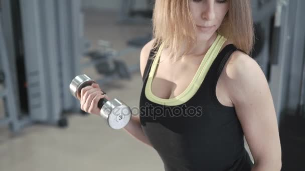 Красивая девушка работает с гантелями в тренажерном зале в 4K — стоковое видео