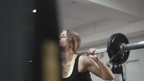 Mira a la chica haciendo sentadillas con barra en el gimnasio en 4K — Vídeos de Stock